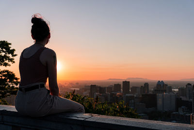 Women looking at cityscape against sky during sunset