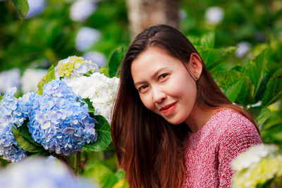 Portrait of smiling young woman against plants