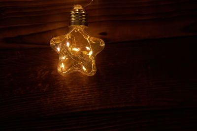 Low angle view of illuminated light bulb on wall