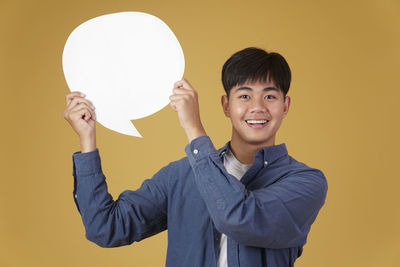 Portrait of young man standing against yellow background