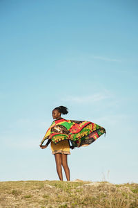 Woman looking away while standing on grass against sky