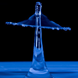 Close-up of water splashing on glass against black background