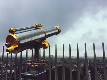 Close-up of wet coin-operated binoculars against sky