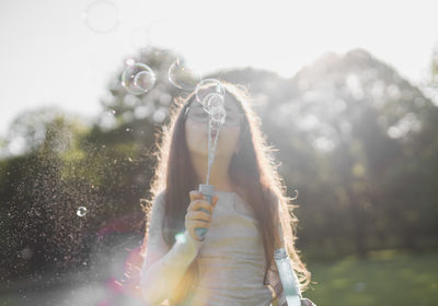 Blurred background of a child girl blowing soap bubbles in the park.