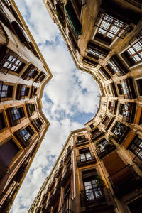 Low angle view of buildings against cloudy sky