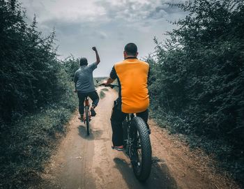 Rear view of man riding bicycle on road