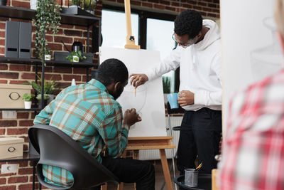 Side view of male friends working at workshop