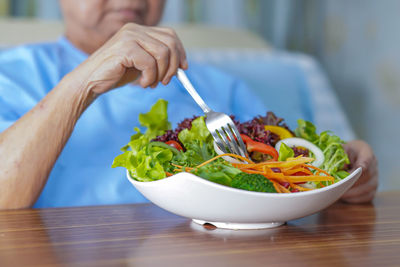 Midsection of man preparing food in bowl on table