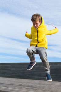 Full length of boy with yellow umbrella against sky