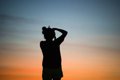 Silhouette woman standing against sky during sunset