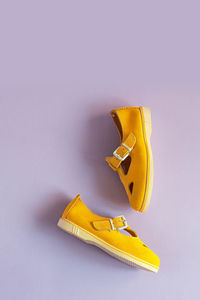 Women's summer yellow sandals on lilac background with copy space. vertical photo. view from above.