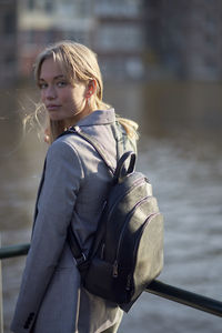 Portrait of woman standing against lake in city