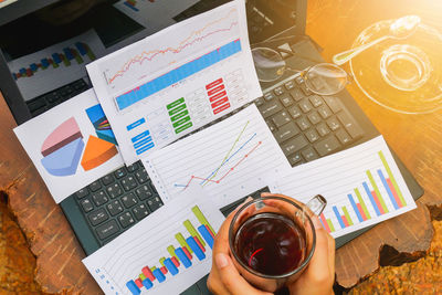 Cropped image of woman holding black coffee over documents