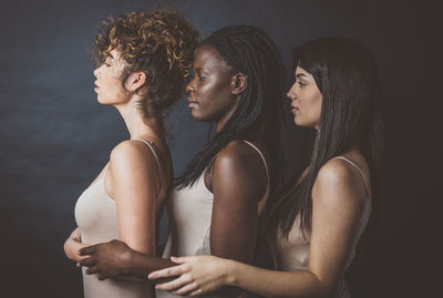 Side view of young woman standing against black background