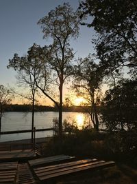 Silhouette trees by lake against sky during sunset