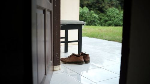 Close-up of brown shoes on floor by window