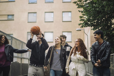 Cheerful teenage friends enjoying while walking together in front of building