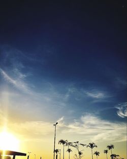 Low angle view of silhouette vapor trail against sky