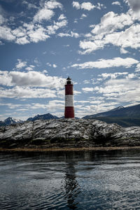 Lighthouse by mountain against sky