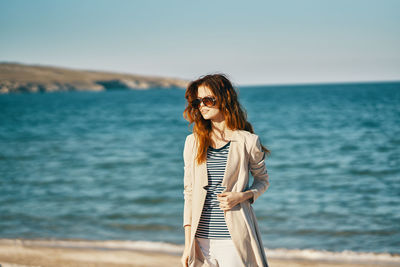 Woman standing by sea against sky