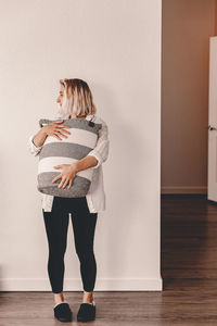 Full length of woman standing against wall at home