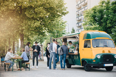 Male and female customers standing by food truck