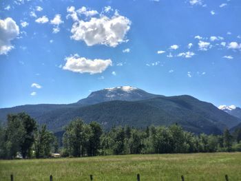 Scenic view of green landscape and mountains against sky