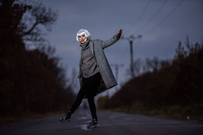 Full length portrait of senior woman on road during winter