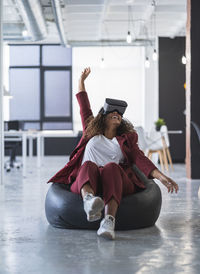 Full length portrait of young woman sitting on floor