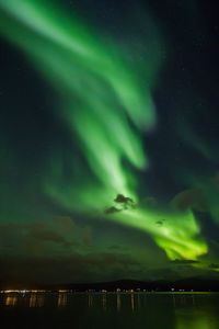 Scenic view of lake against dramatic sky at night