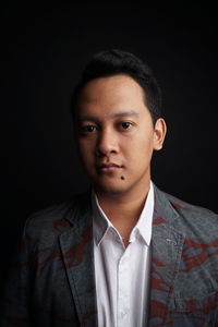 Portrait of young man against black background