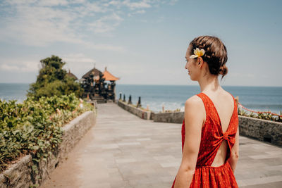 Woman with umbrella on shore against sky