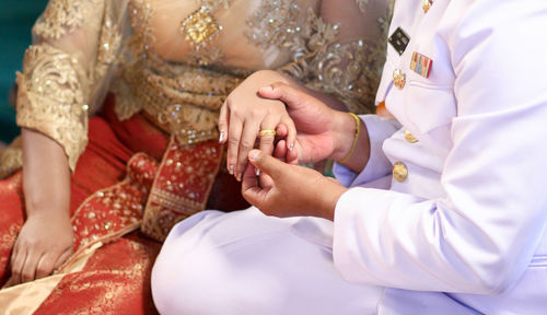 Midsection of wedding couple exchanging finger rings during ceremony