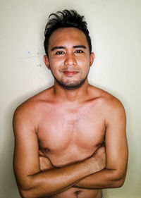 Portrait of shirtless man standing against wall