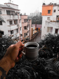 Man holding coffee cup and buildings in city