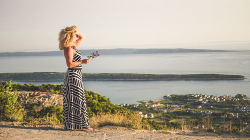 Woman standing by sea against clear sky