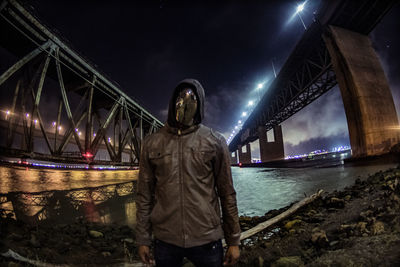 Man standing on bridge against sky at night