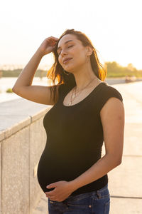 Beautiful young woman standing against sea against sky