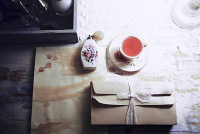 High angle view of tied up envelops with perfume sprayer and tea on table