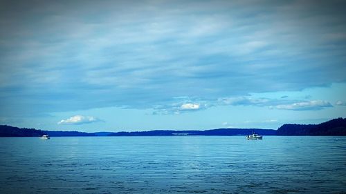 Boats in sea against cloudy sky