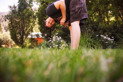 Portrait of smiling young woman bending in backyard