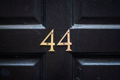 House number 44 on a dark wooden front door in london 