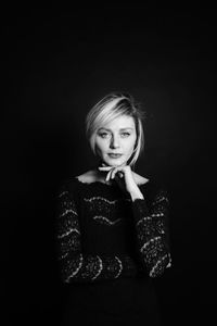 Portrait of woman standing against black background