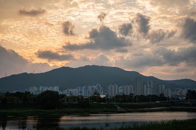 Scenic view of city by mountains against sky during sunset