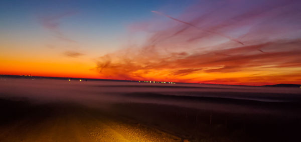 Scenic view of sea against dramatic sky during sunset