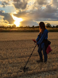 Full length of man standing on field against sky during sunset