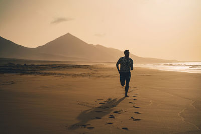 Rear view of man walking on land during sunset