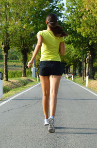 Woman jogging on road against trees