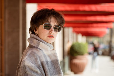 Portrait of young woman in gray coat and sunglasses