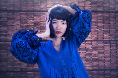 Portrait of woman in blue dress against wall